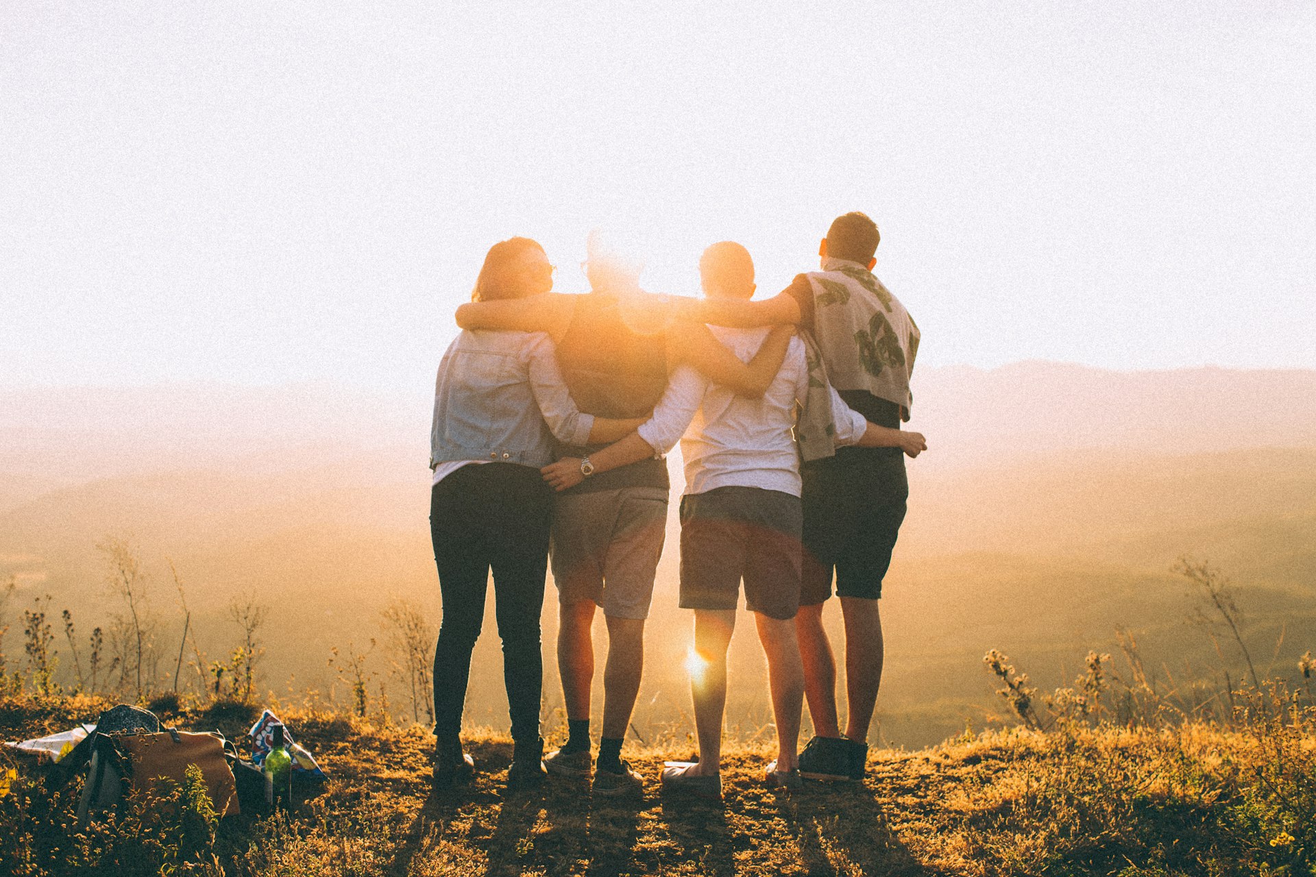 Friends standing together at sunset, looking out over the hills
